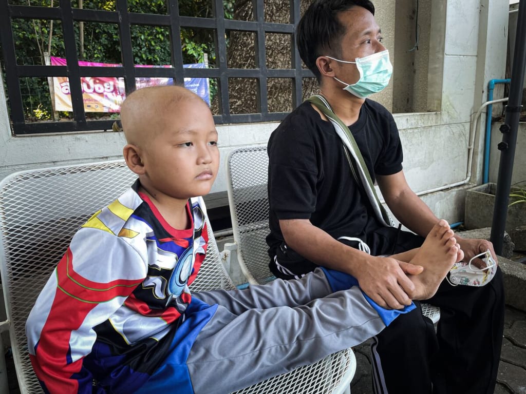 A boy sits with his feet propped up on his father's lap beside him